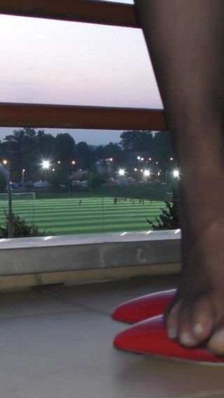 Dipping classic red high heels on balcony